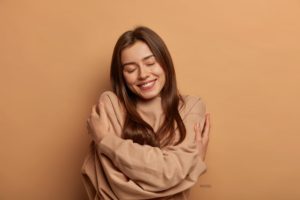 Woman wrapping arms around herself, showing self-love